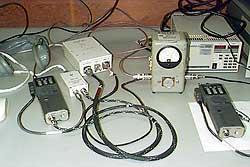 The test bench at Frank Bauer's flight hardware lab at Goddard Space Flight Center. The test setup is for hardware "touch tests," Marchant explained. "This makes sure the external surfaces of the hardware won't get hot enough to harm an astronaut," he said. Standard tests involve keying the gear for a certain period of time and measuring the external temperature of the equipment. The headset at the upper left is a nonflight version of the standard astronaut headset. The smaller white box is the audio-power interconnect. The larger white box is the packet TNC.